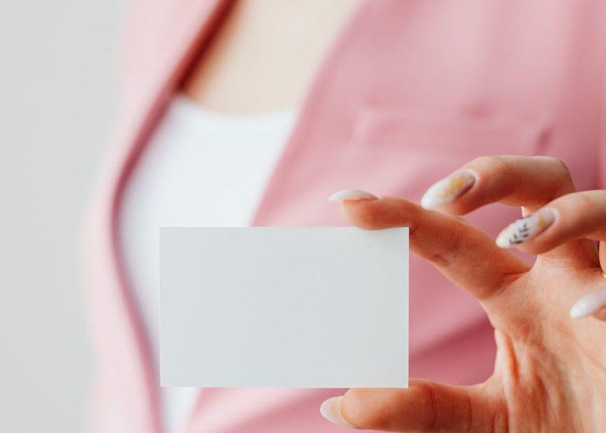 woman in pink blazer holding a blank card